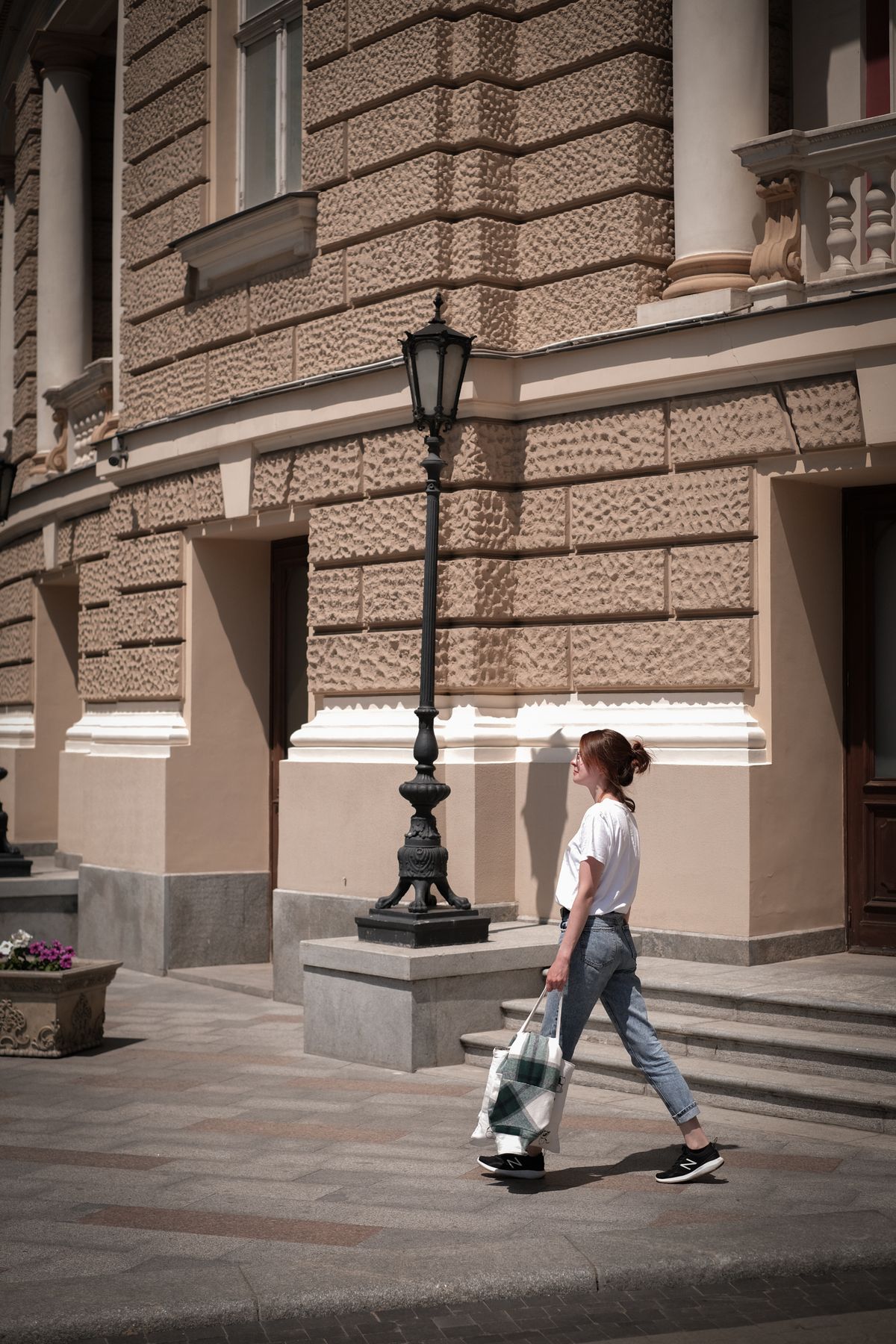 Woman in a white tee and jeans strolling past a historic building